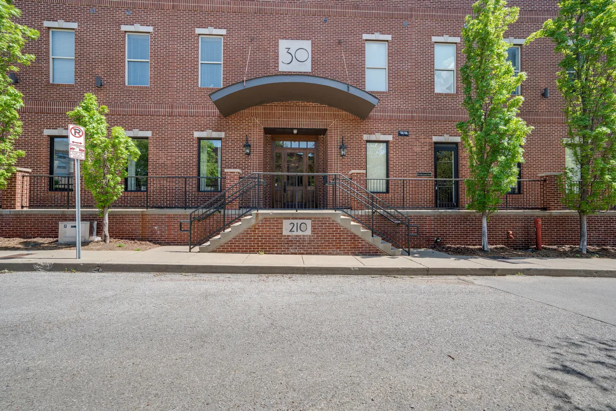 This image shows the main entrance of a modern residential building, featuring a brick facade, well-maintained landscaping, and clear house number signage. The inviting front steps set a welcoming tone for arrivals.