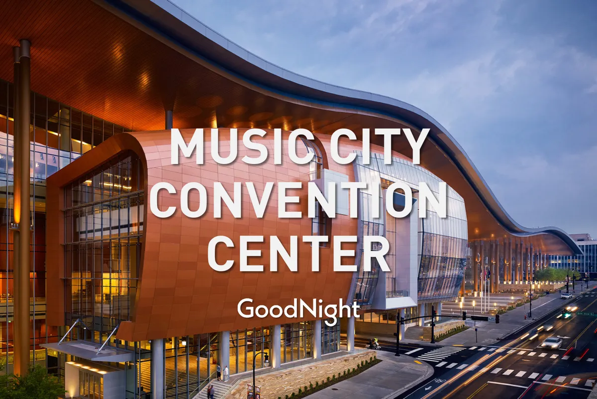 The image showcases the modern glass-and-steel facade of the Music City Center, Nashville’s premier convention and business hub. Its distinctive curved roof and illuminated signage are visible, with a lively atmosphere suggesting active events or gatherings.