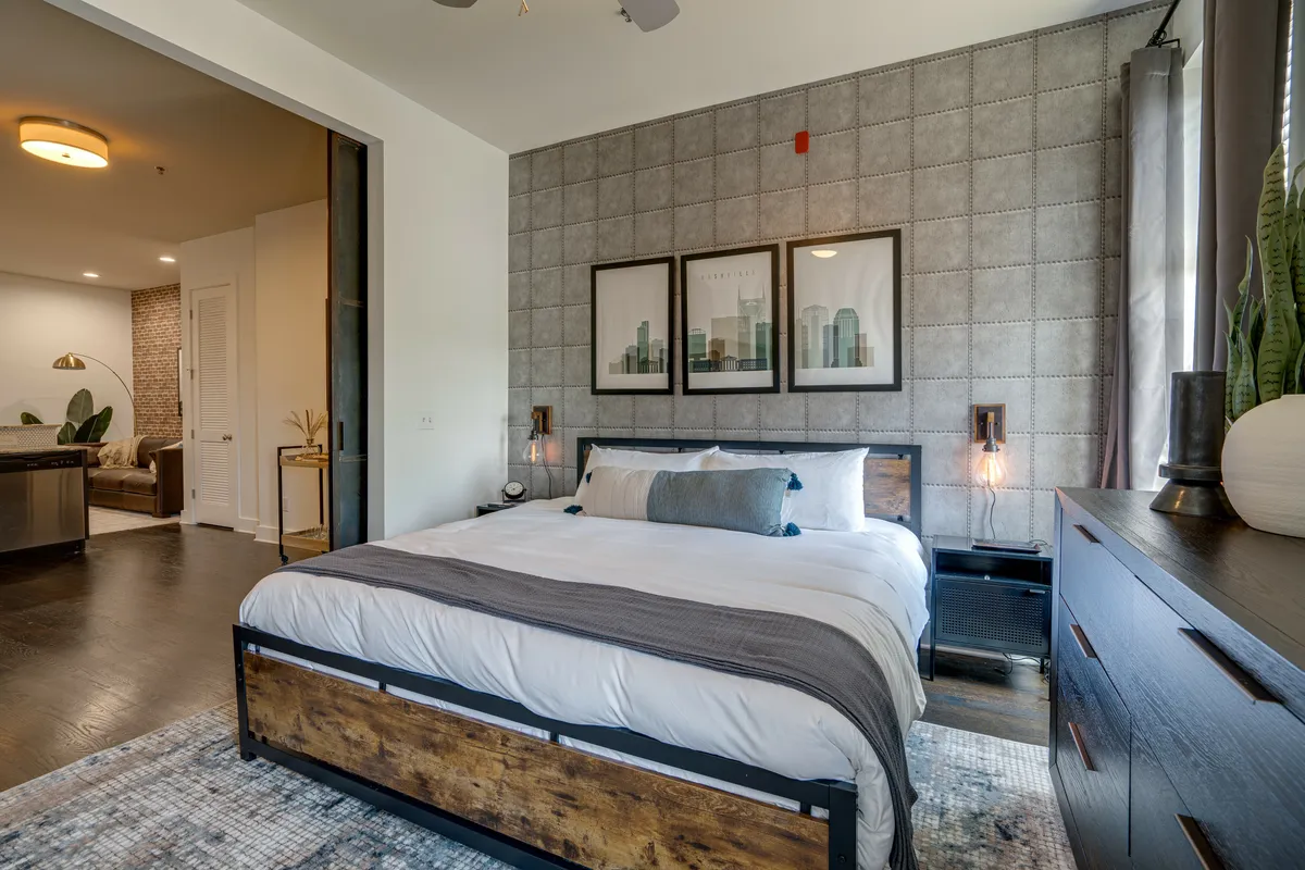 A cozy bedroom with a king-size bed, stylish artwork above the headboard, and nightstands topped with warm bedside lamps. Natural light filters in, creating an inviting and restful atmosphere.